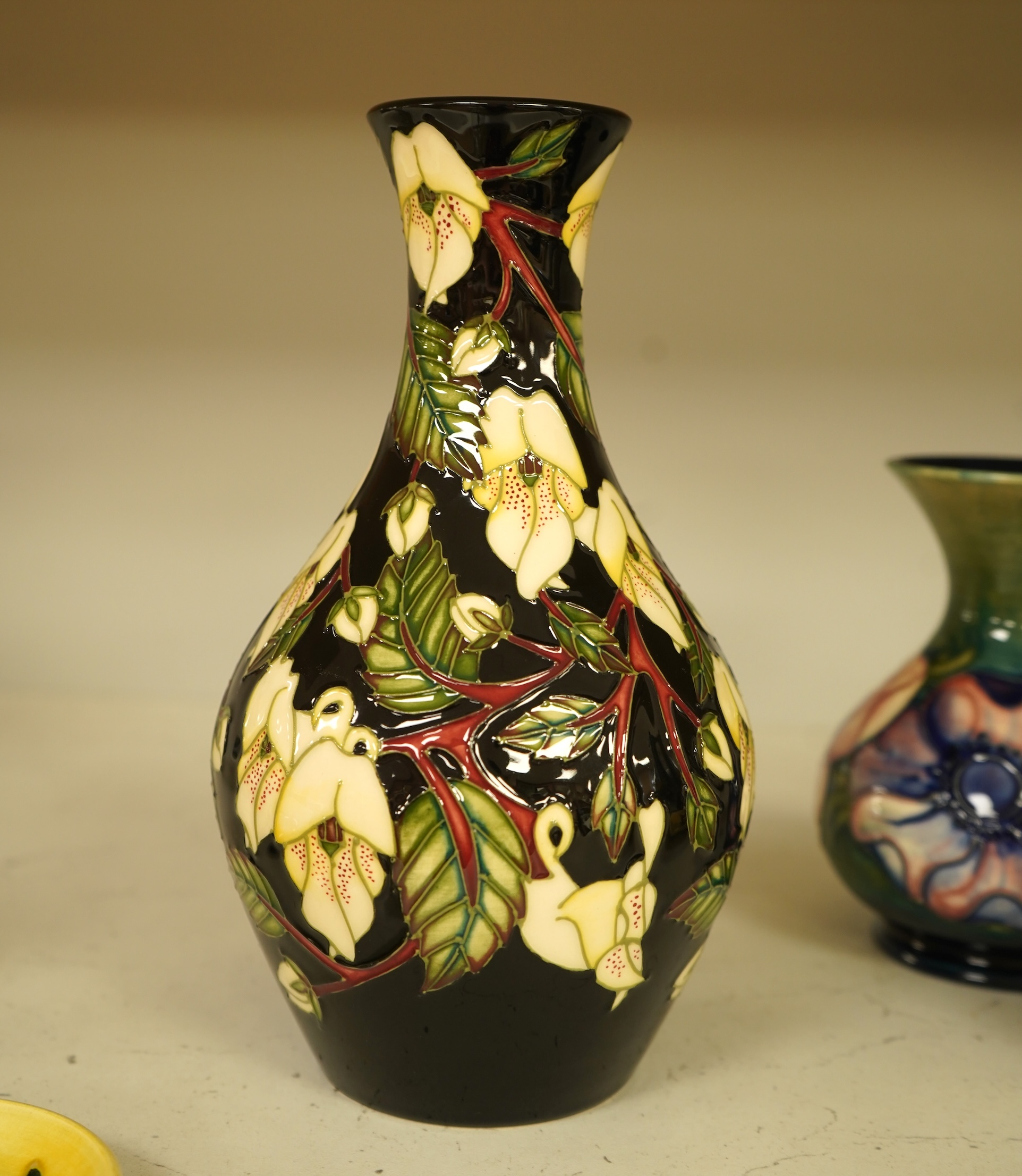 A collection of modern Moorcroft to include a mountain gold pattern vase, two pin dishes and a Hibiscus pattern candlestick, largest 20cm high